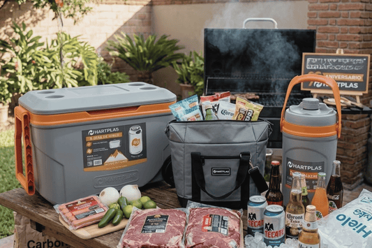 Evento al aire libre con mesas decoradas y personas disfrutando de alimentos y bebidas frías